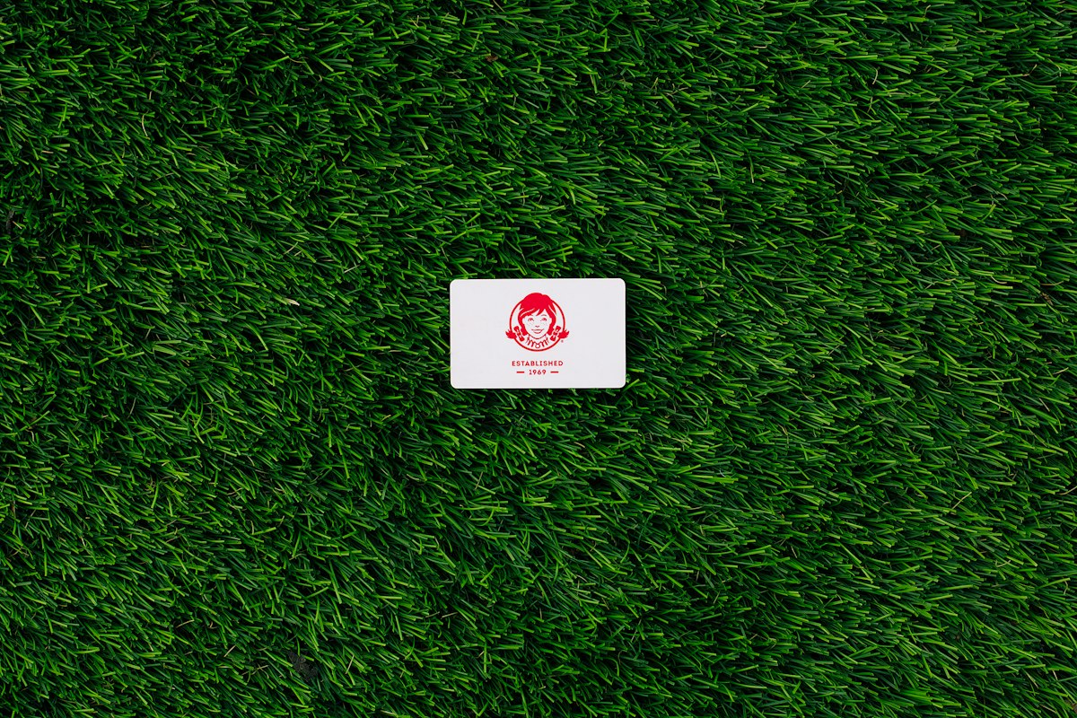 a white square sticker sitting on top of a lush green field