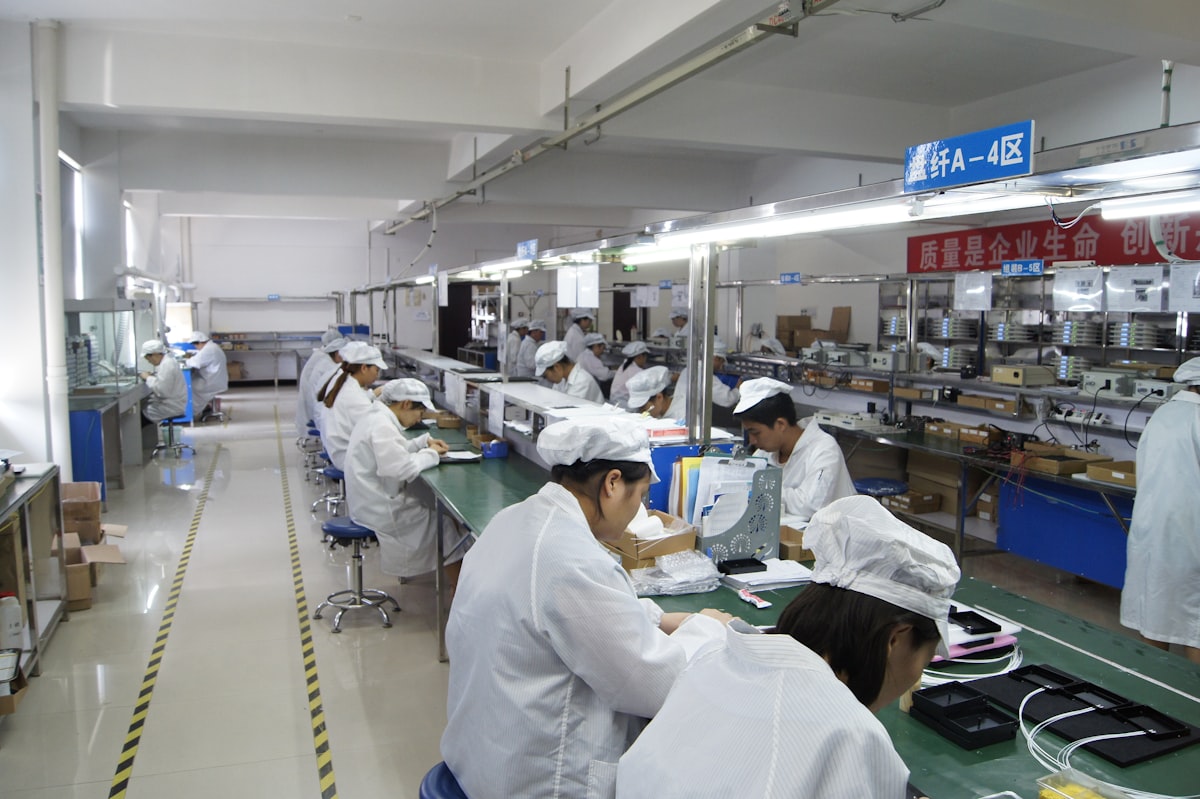 Workers assemble electronics on a factory production line.