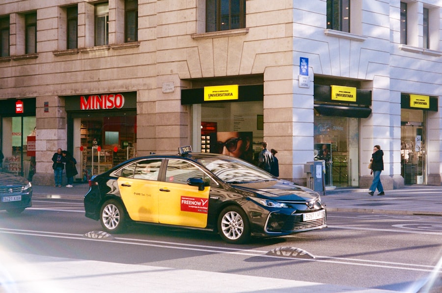 A yellow and black taxi drives down a city street.