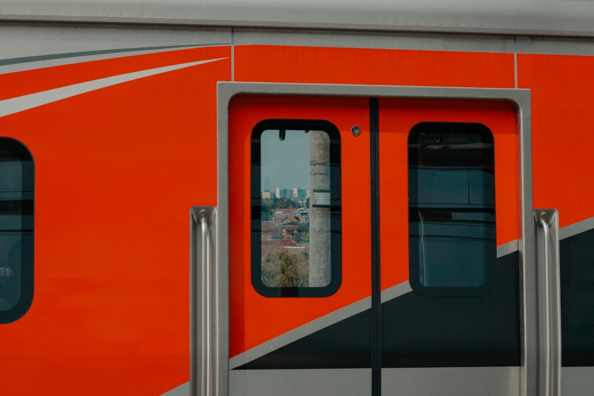 Orange train doors with city reflection in window