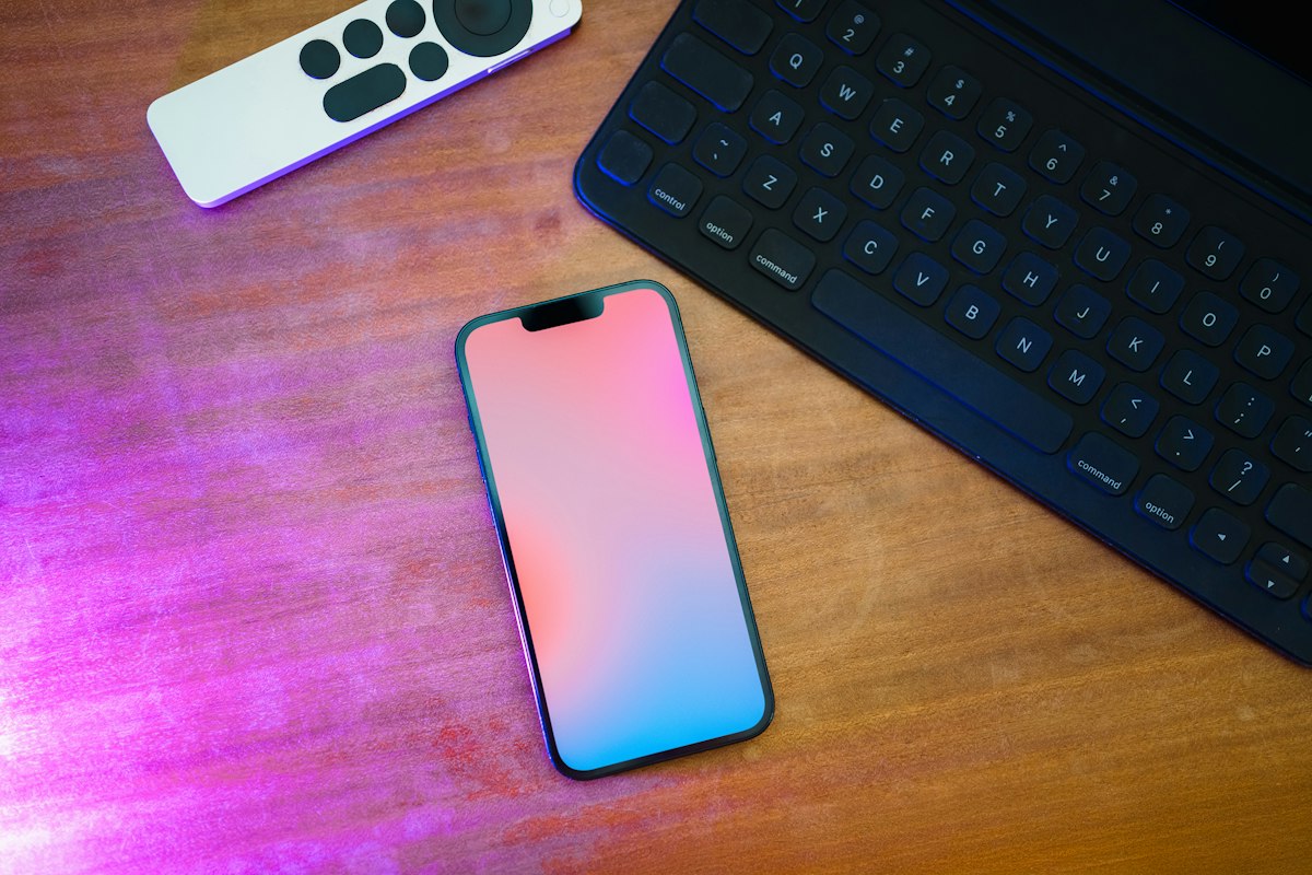 A cell phone sitting on top of a wooden table next to a keyboard