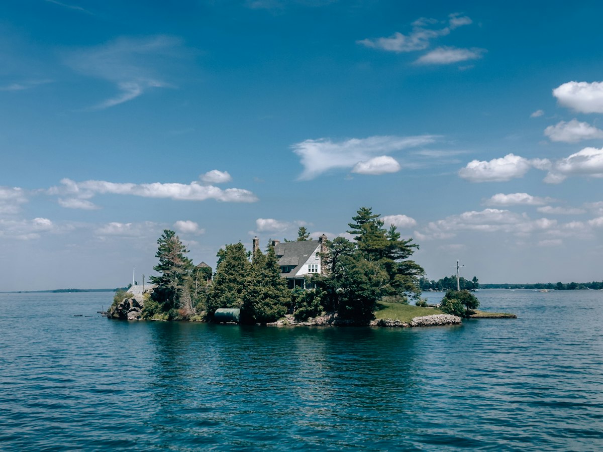 House and trees on a small island in blue water