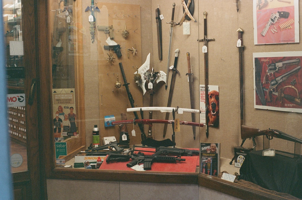 A display case filled with swords, daggers, and firearms.