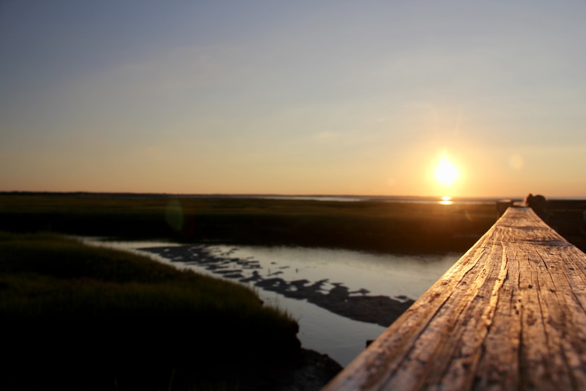 the sun is setting over a wooden pier