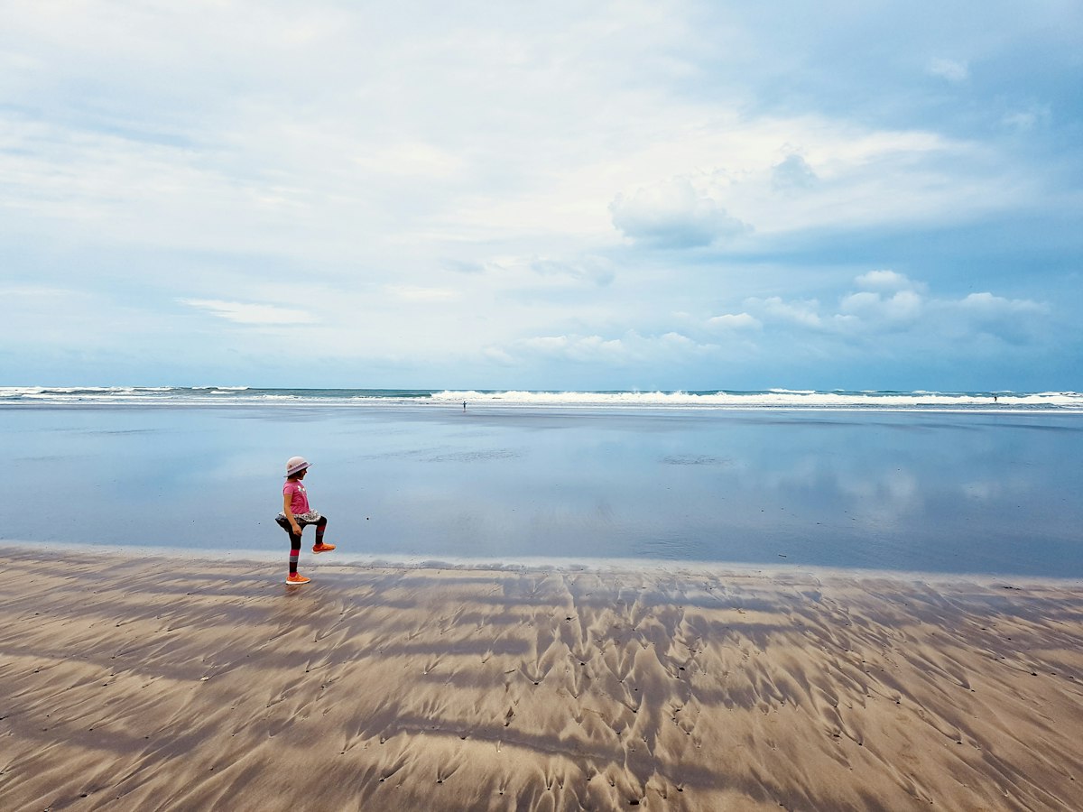 Person standing on a wet sandy beach by the ocean