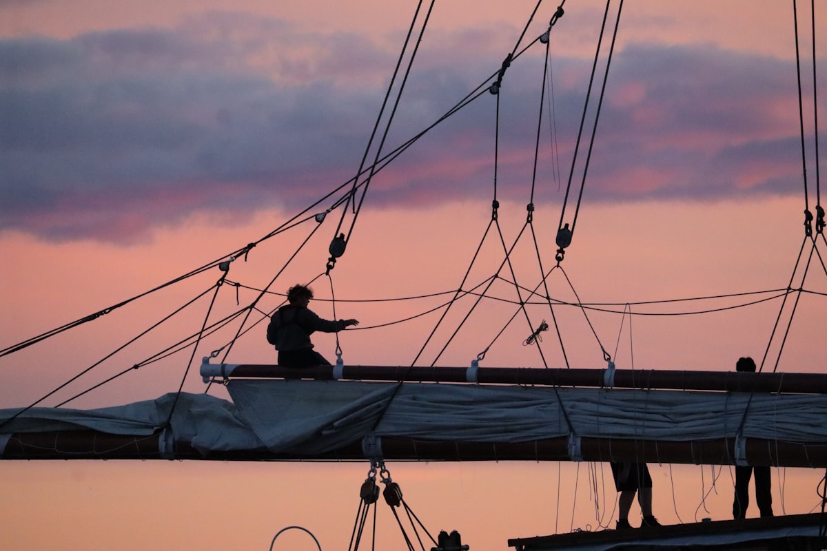 Sailors working on a sailboat at sunset