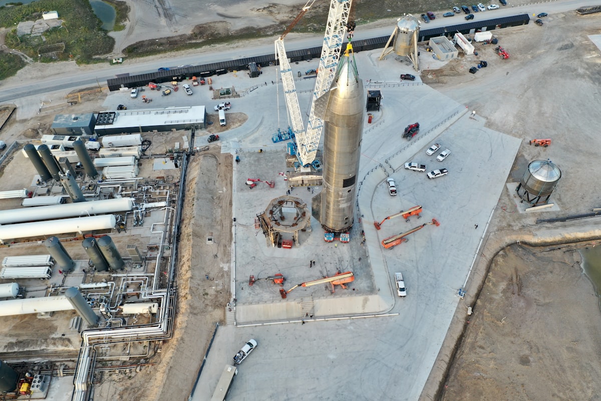 Rocket assembly at a launch facility with cranes and vehicles.