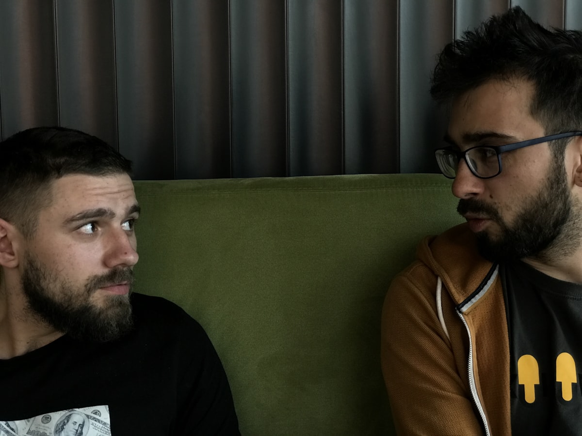 a couple of men sitting on top of a green couch