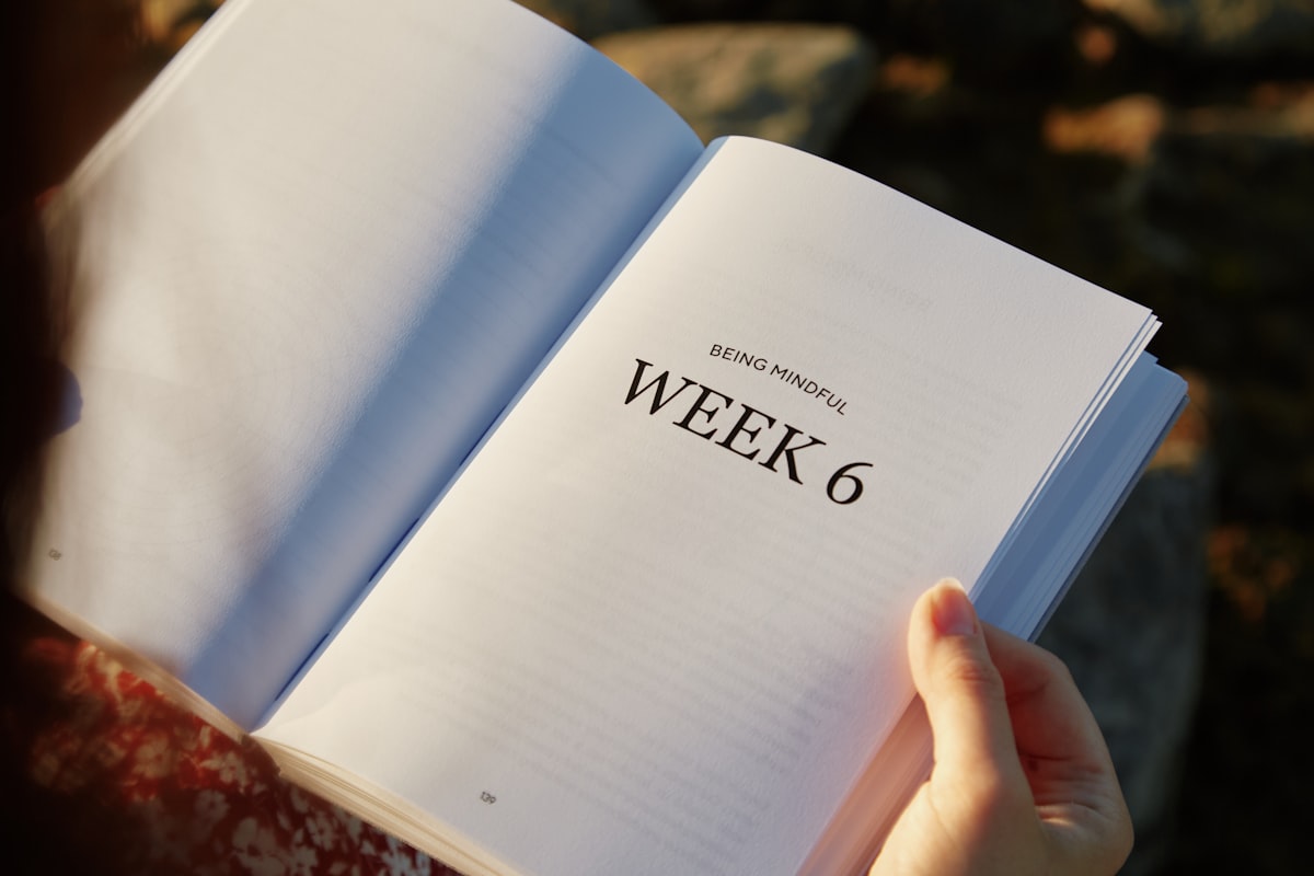 A person holding a book with the word week 6 written on it