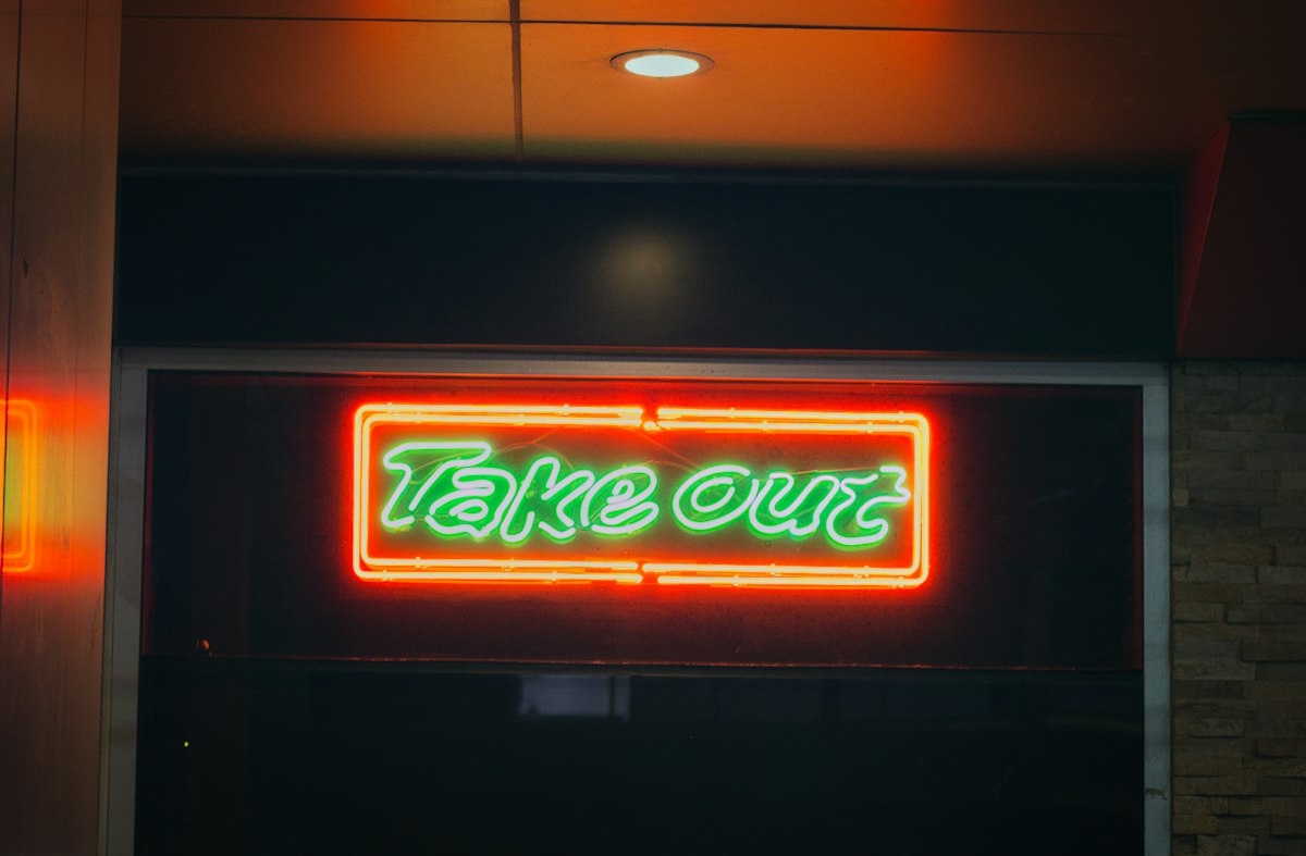 Neon take out sign glows at night