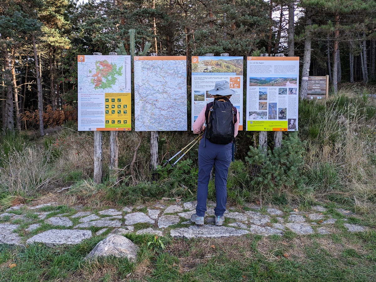 Hiker consults maps at a trail information board.