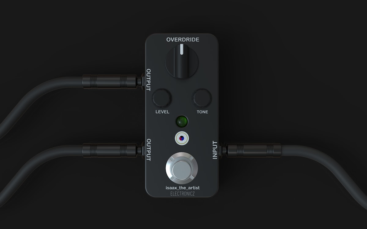 A black guitar pedal with cables connected.