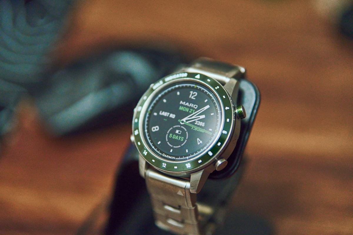 A silver smartwatch with a green bezel on display