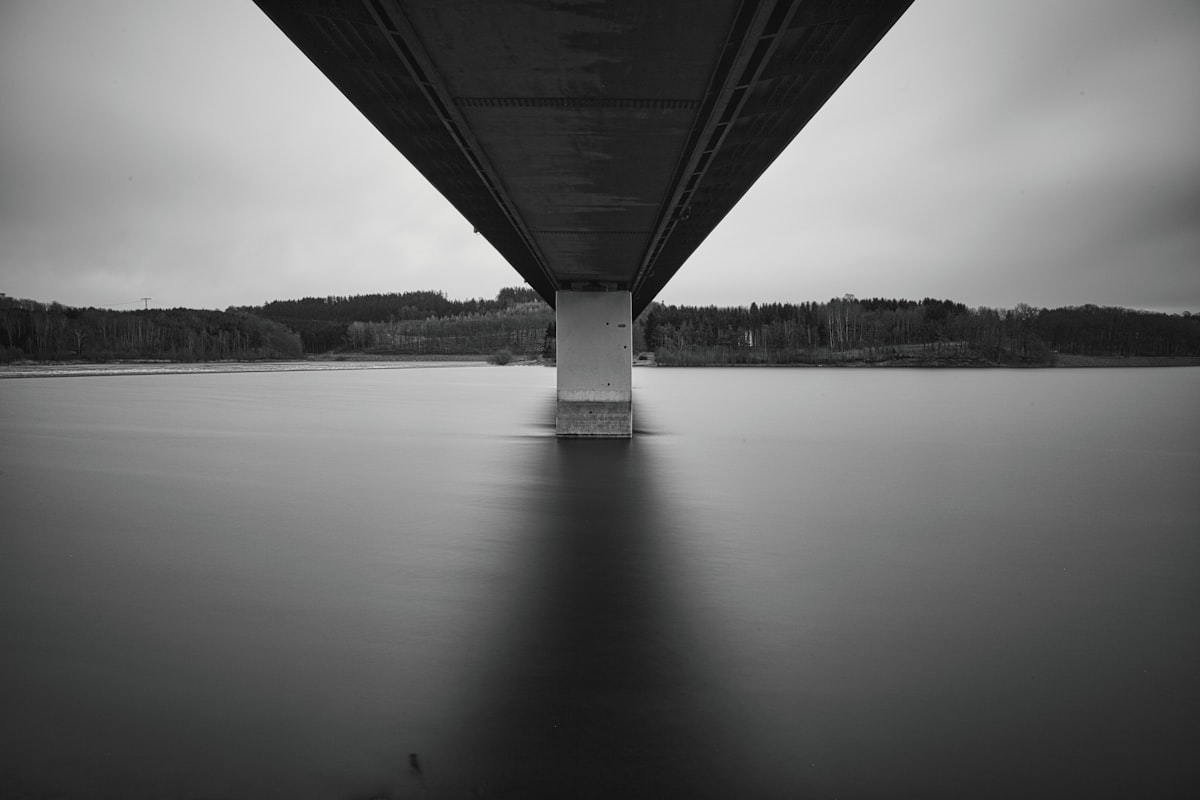 Underneath a bridge over calm water at dusk