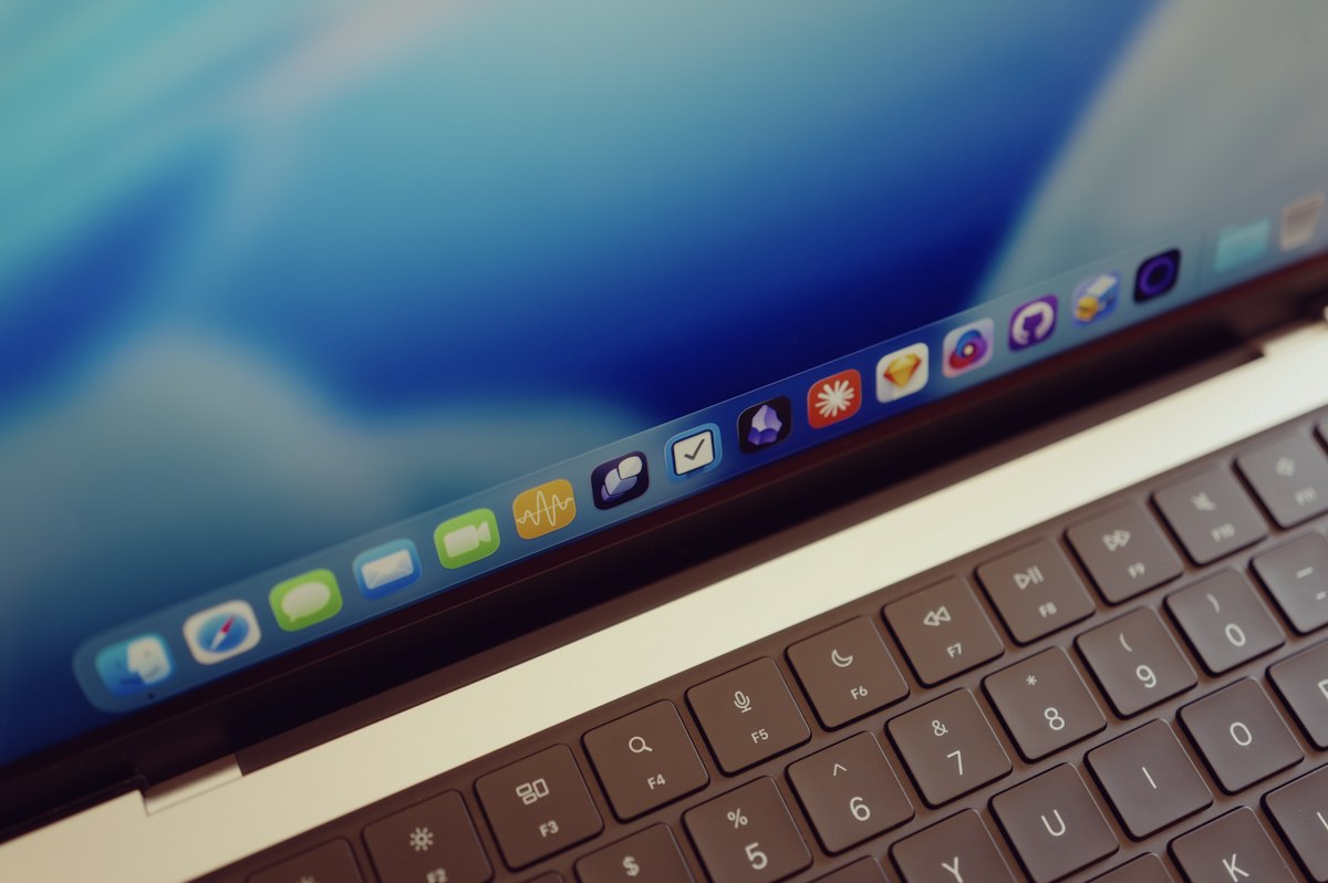 A laptop keyboard and a screen displaying a row of colorful application icons