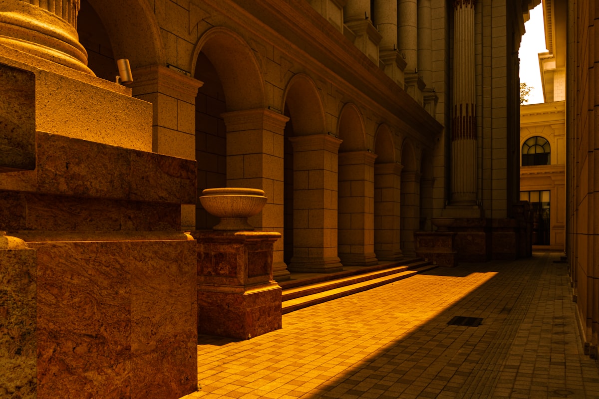 Sunlit colonnade with patterned pavement and stone architecture