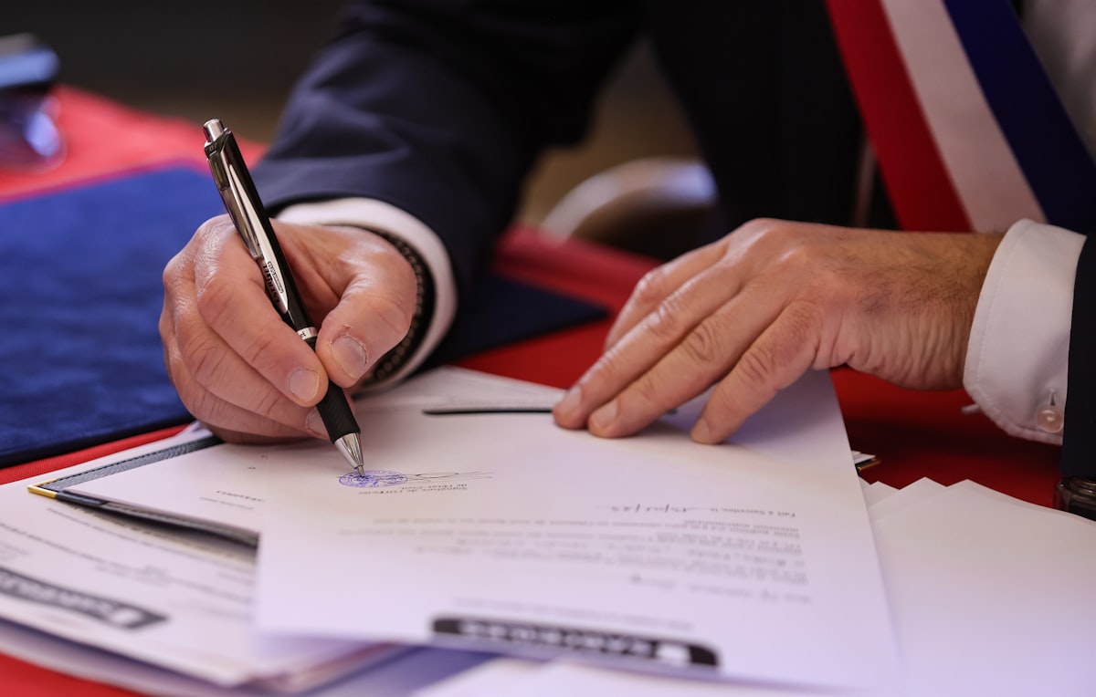 A person signs a document with a pen.