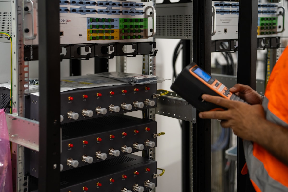 Technician inspecting server racks with a handheld diagnostic tool.